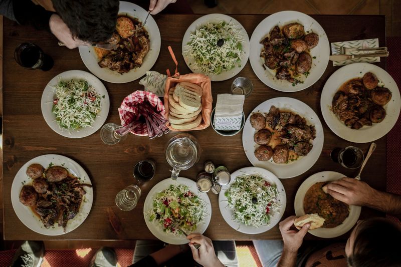 Friends and family sharing plates of food around a wooden table